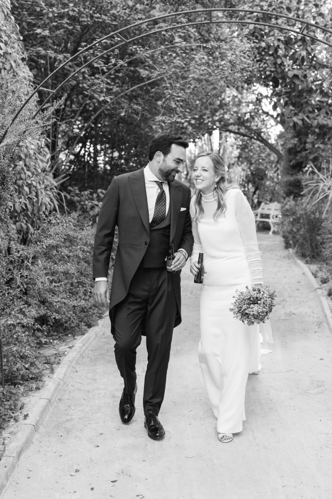 Novios caminando y riendo por el jardín