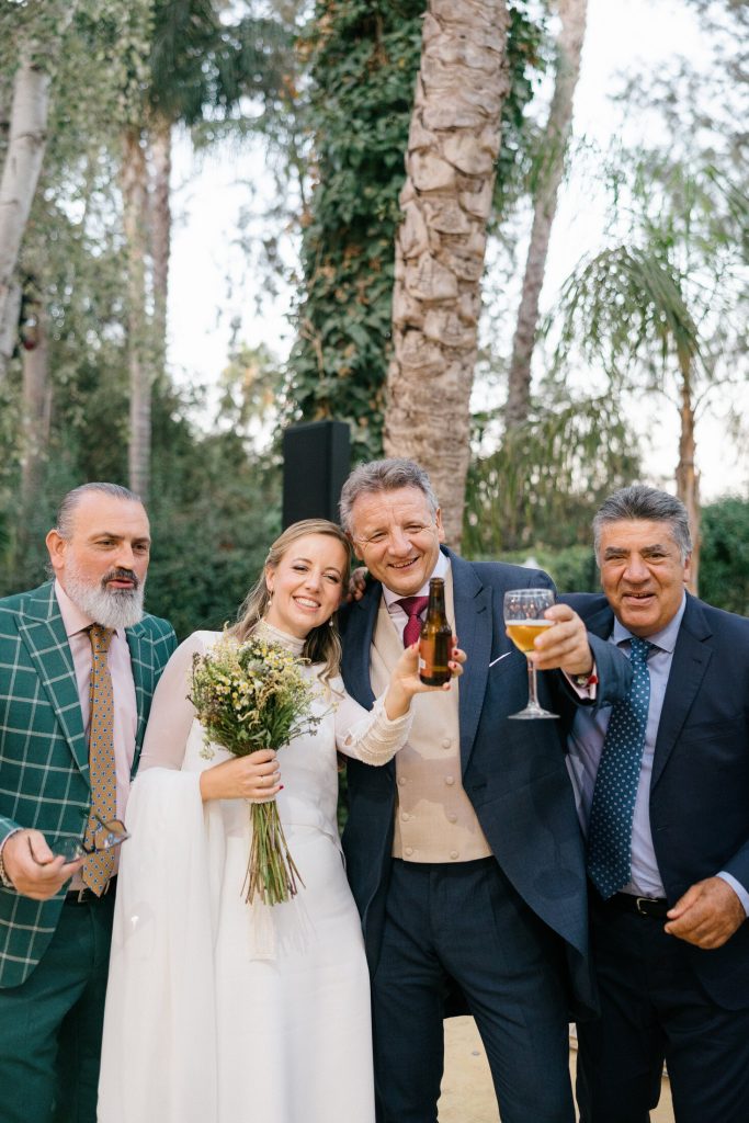 Novia caminando junto a invitadas bajo un túnel de luces