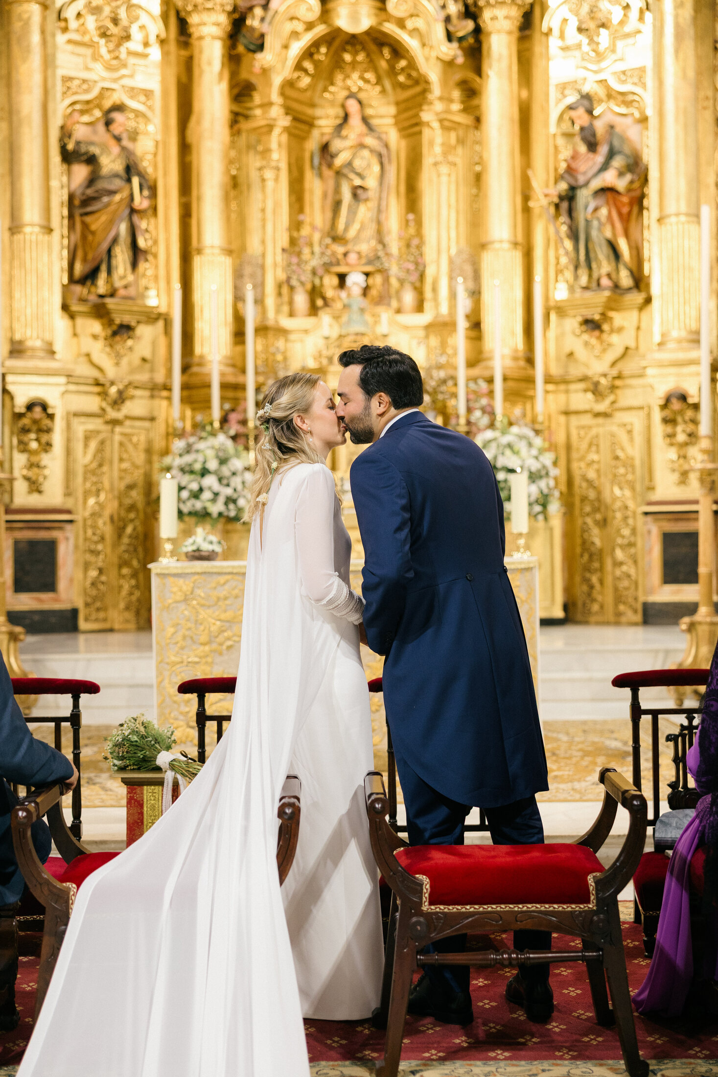 Novios besándose ante el altar dorado de la Parroquia de San Andrés