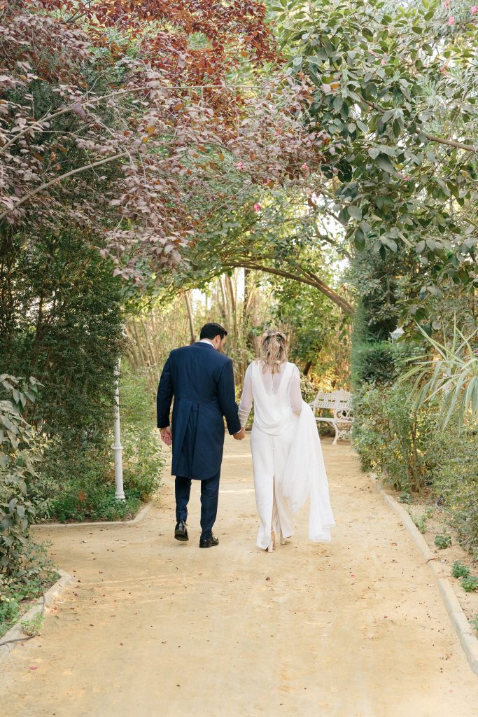 Novios paseando bajo un arco de vegetación