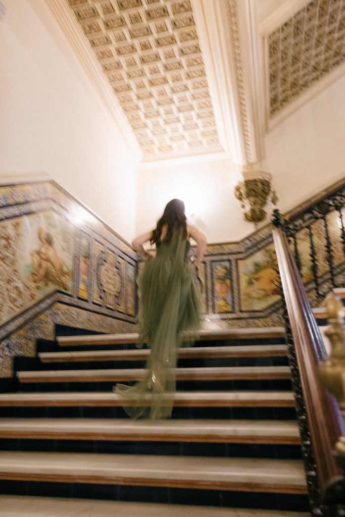 Novia bajando una escalinata clásica antes de la ceremonia en Sevilla
