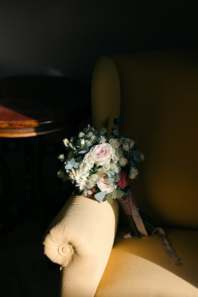 Ramo de novia reposando sobre un sillón junto a un rincón con luz cálida