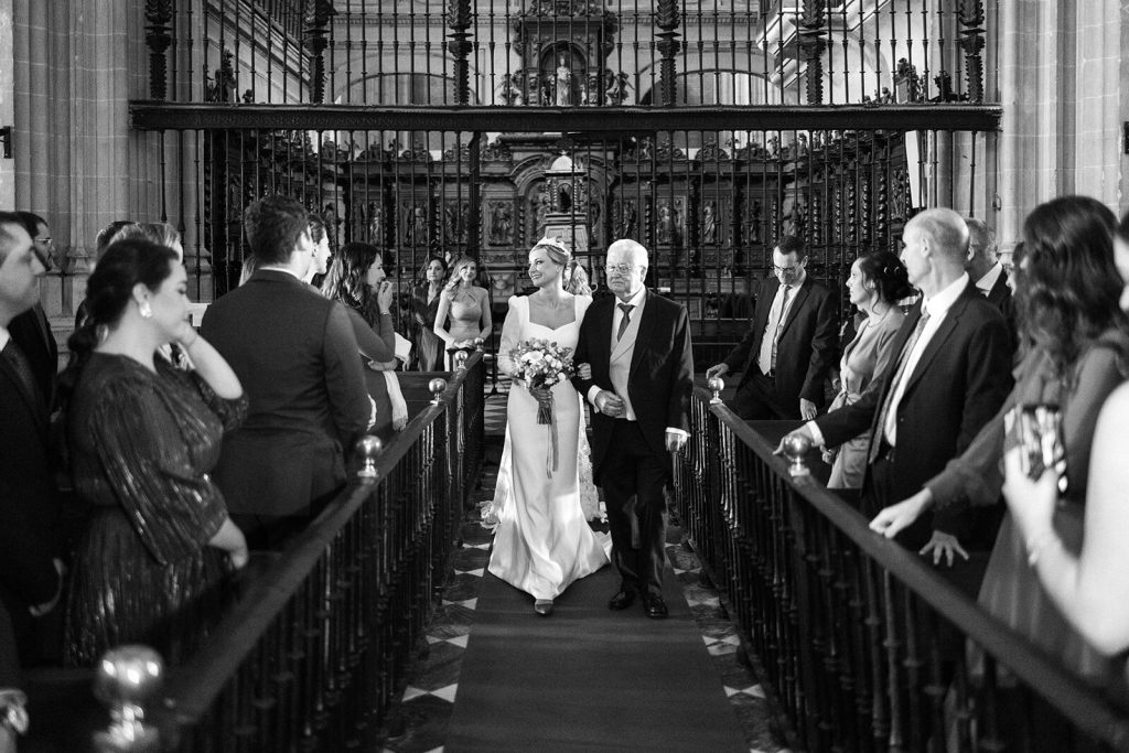 Novia caminando del brazo de su padre por el pasillo de la iglesia