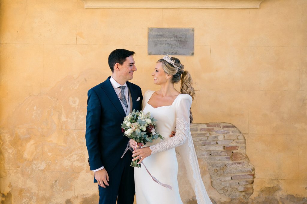 Retrato de los novios junto a un muro de piedra dorada