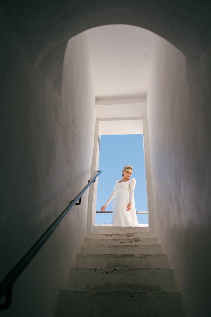 Silueta de la novia asomada en una escalera con vistas al cielo