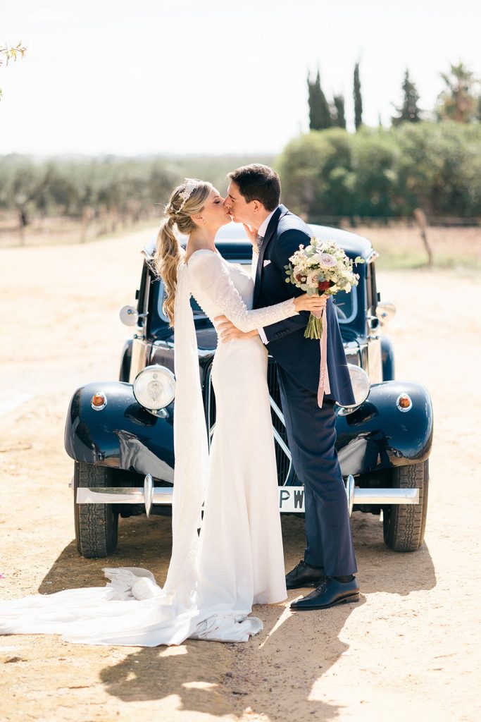 Los novios junto a un coche de época en los jardines de La Hacienda de Medina
